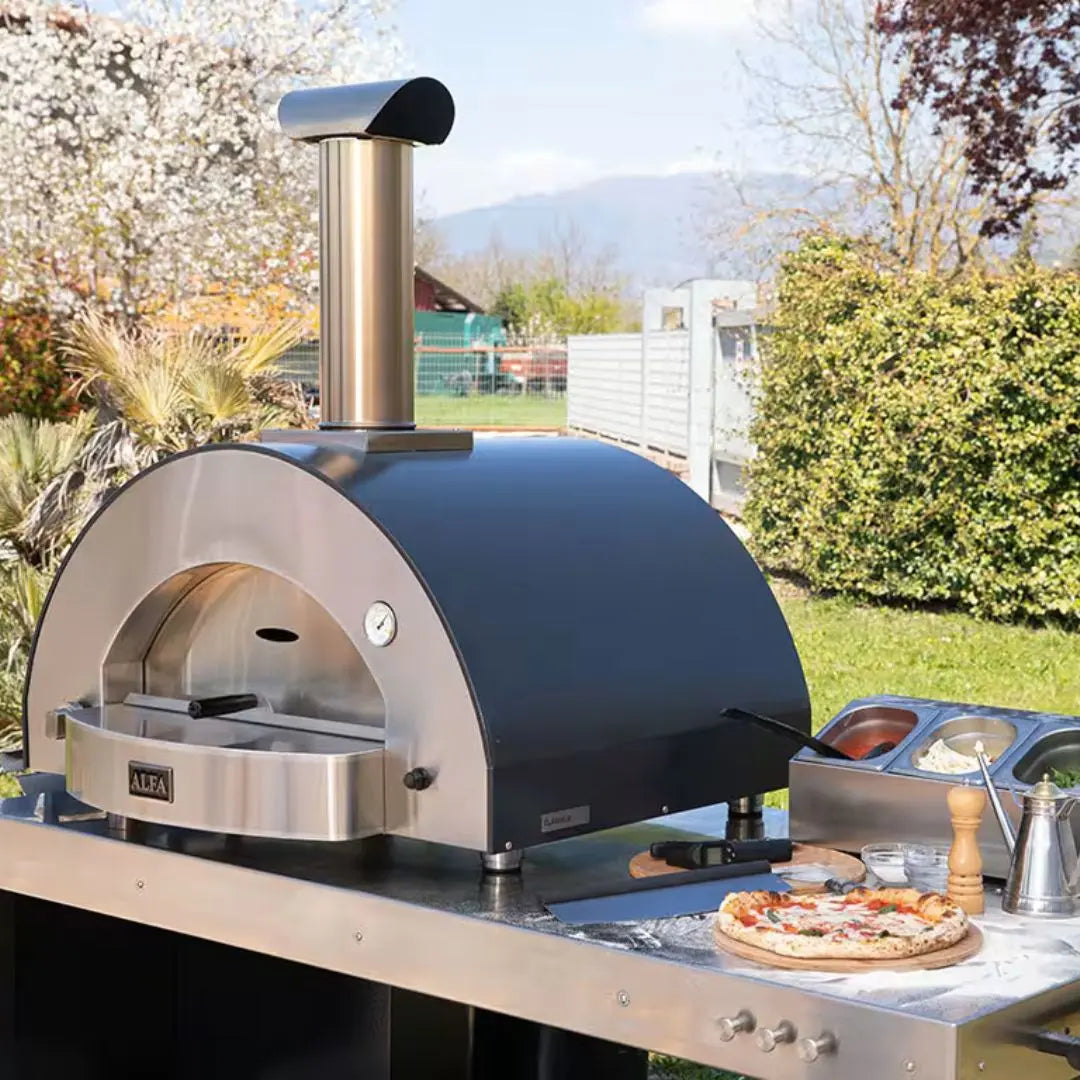 Outdoor Alfa Classico 4 Pizze Hybrid Gas pizza oven with a pizza on a table in a garden setting