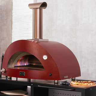 Alfa Moderno 2 Pizze Hybrid Pizza Oven in Antique Red outside with pizza being prepped