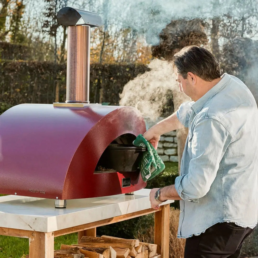Alfa Moderno 2 Pizze Wood Fired Pizza Oven in Antique Red with man adding hot dish
