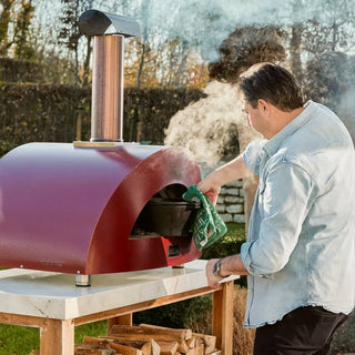 Alfa Moderno 2 Pizze Wood Fired Pizza Oven in Antique Red with man adding hot dish