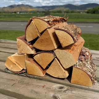 Stack of chopped birch kiln dried cooking logs for pizza oven on bench table