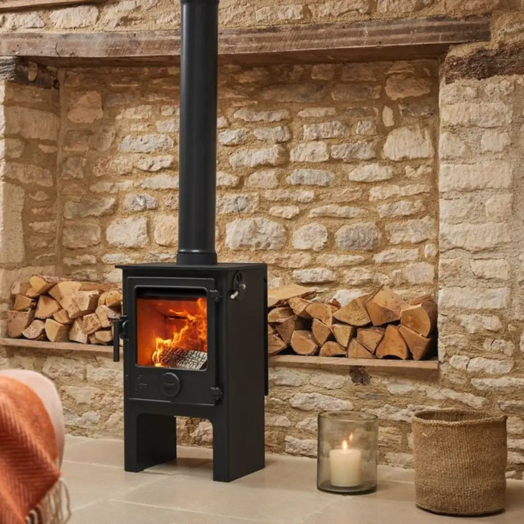 Dean Forge Dartmoor 5 Midi Eco Stove - 5kW with stone wall, stacked logs and candle
