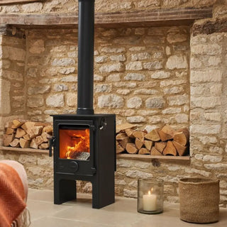 Dean Forge Dartmoor 5 Midi Eco Stove - 5kW with stone wall, stacked logs and candle