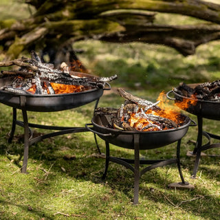 Three outdoor Dean Forge Firebowl fire pits with flames on a grassy area
