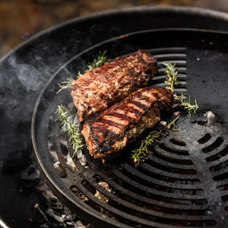 Two grilled steaks on Dean Forge Moorland Firebowl and Swing Arm Set grill with herbs
