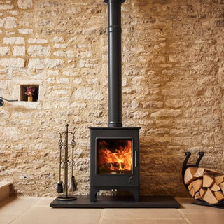 Dean Forge Woodbury 5 Eco Stove - 5kW on black hearth against stone wall with log holder