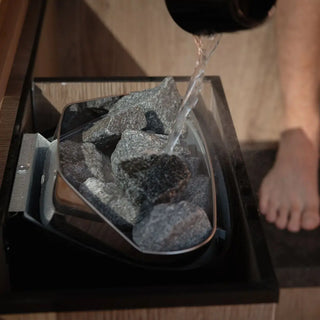 Person pouring water onto a kirami sauna heater
