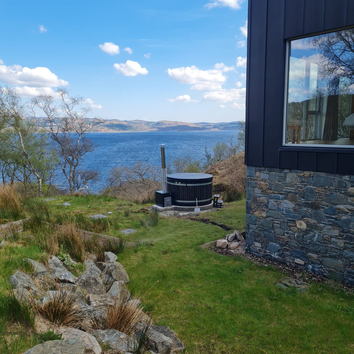 Hot tub in a scenic outdoor setting with a view of a lake and mountains.
