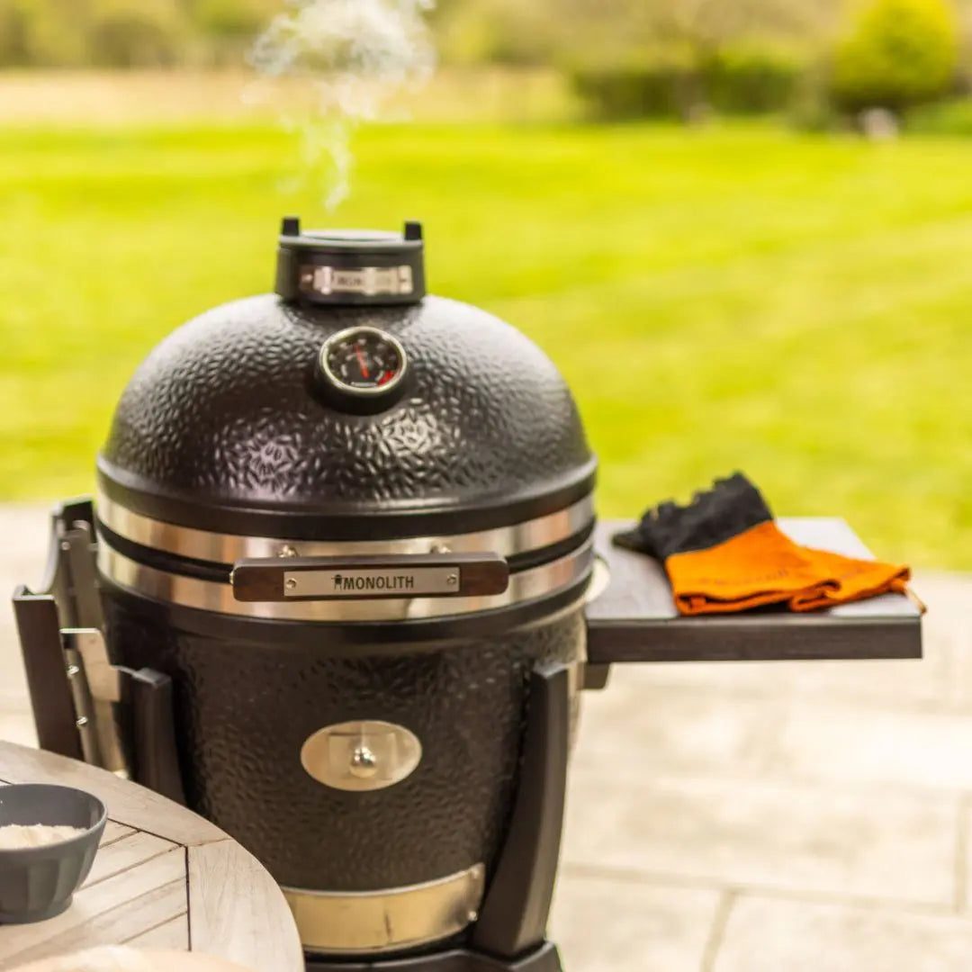 Black Monolith Avantgarde grill on a patio with a grassy area in the background
