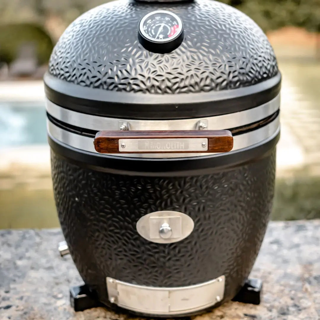 Monolith Avantgarde Black kamado grill with textured surface on a blurred natural background