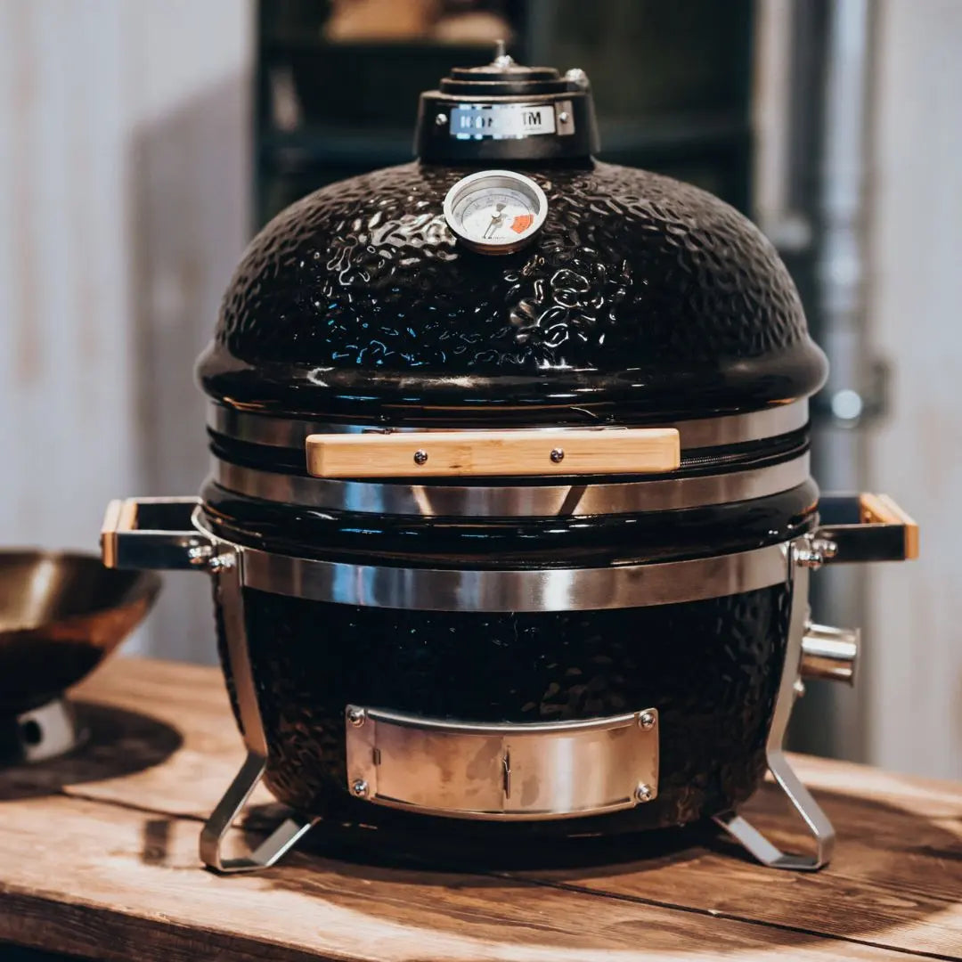 Monolith ICON 53cm Black ceramic grill with a thermometer on a wooden surface