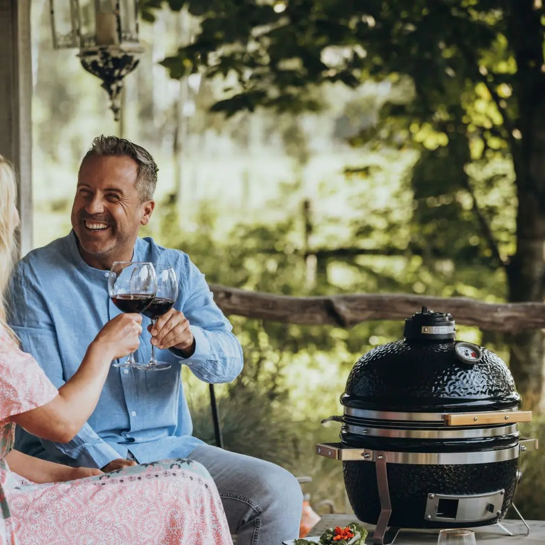 Couple enjoying wine by Monolith ICON 53cm black barbecue kamado grill outdoors