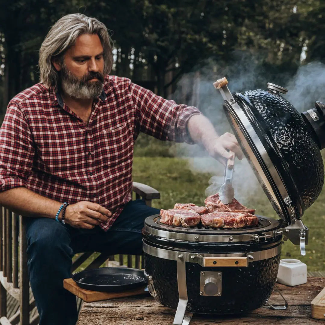 Monolith ICON 53cm Man grilling meat on a barbecue grill outdoors