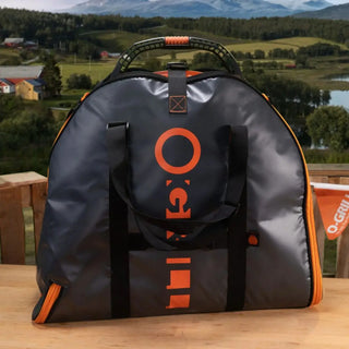 Black and orange bag with O-Grill logo for portable gas bbq grill on a wooden surface with a scenic background