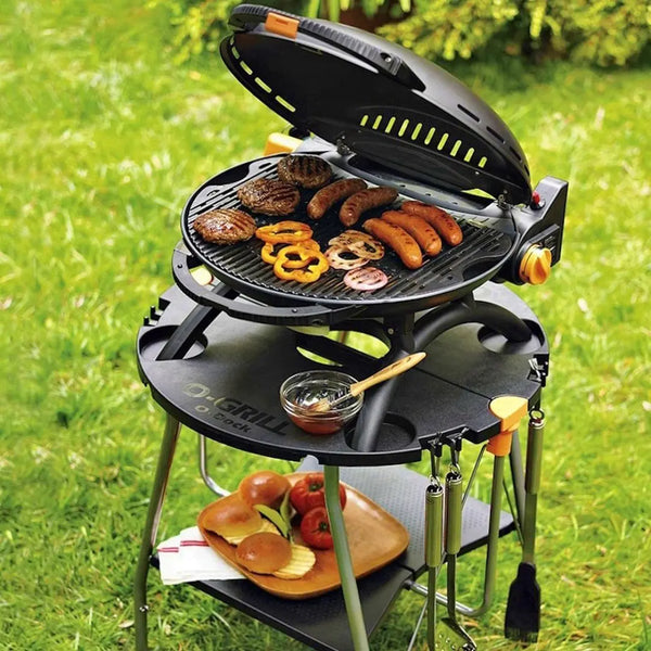 O-Grill portable gas grill bbq with food on a grassy outdoor setting