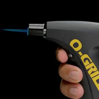 Hand holding a O-Grill torch lighter with a blue flame against a black background