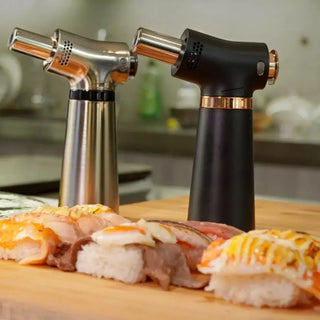 Two kitchen torches on a wooden board with sushi in a kitchen setting