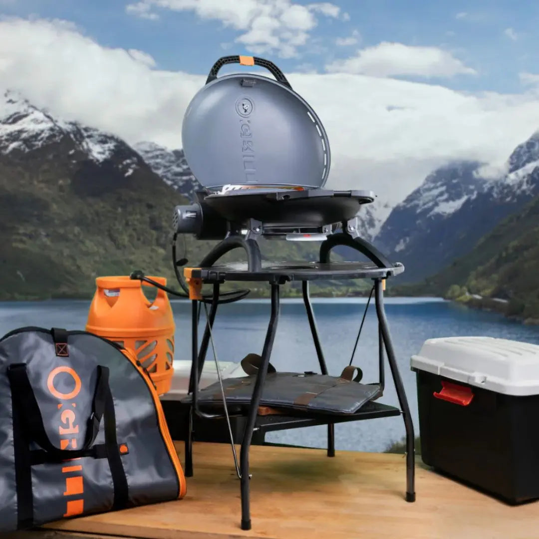 Portable O-Grill on folding table with scenic mountain and lake background