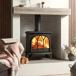 Stovax Huntingdon 30 Wood-burning stove with tracery door in a living room with a fireplace mantle and decorative items.