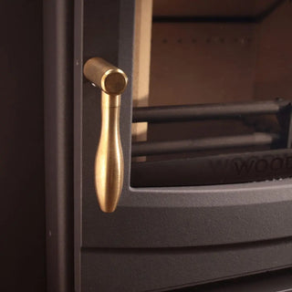 Close-up of brass Woodwarm machined teardrop handle on wood burning stove